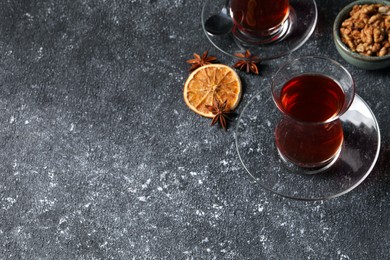 Glasses of traditional Turkish tea and ingredients on grey textured table. Space for text