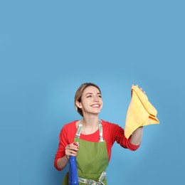 Young housewife with detergent and rag on light blue background