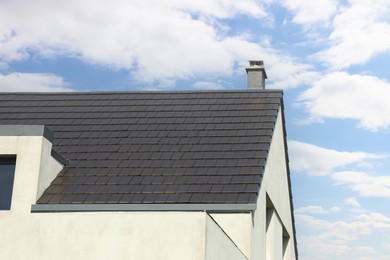 Photo of Modern house with grey roof against blue sky, low angle view