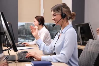 Photo of Call center operators working in modern office, focus on young woman with headset