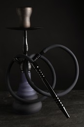 Modern hookah on black table against dark background