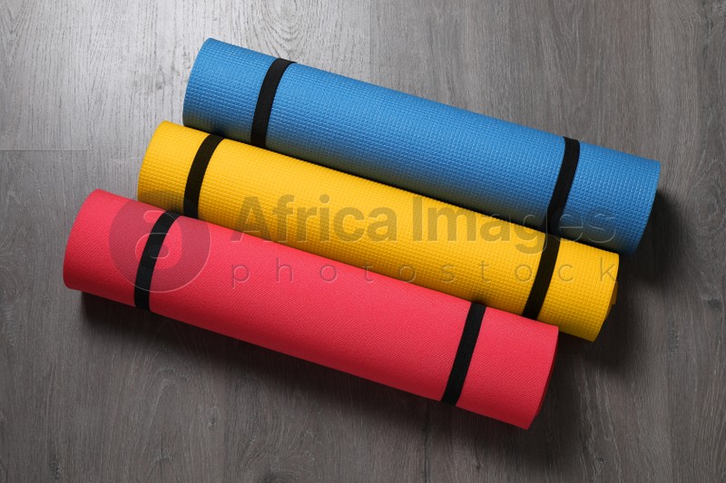 Bright rolled camping mats on grey wooden background, flat lay