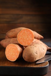 Whole and cut ripe sweet potatoes on wooden board