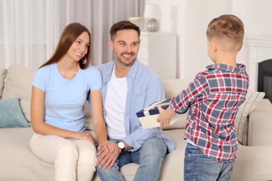 Little boy presenting his parents with gift at home