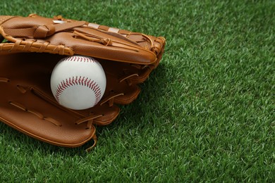 Photo of Catcher's mitt and baseball ball on green grass, space for text. Sports game