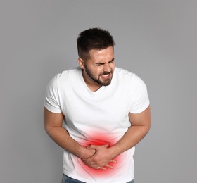 Man suffering from abdominal pain on grey background