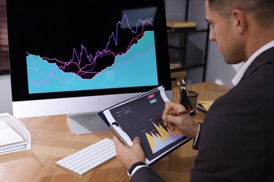 Businessman working with computer and graph in office, closeup. Forex trading