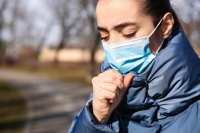 Woman wearing disposable mask outdoors, closeup. Dangerous virus