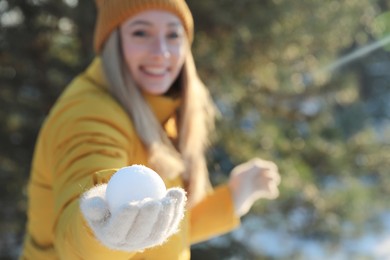 Woman with snowball outdoors, focus on hand. Space for text