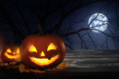 Image of Scary Jack O Lantern pumpkins under full moon on Halloween. Space for text