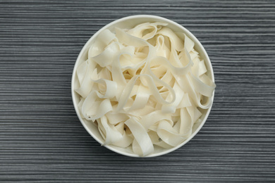 Tasty rice noodles on black wooden table, top view