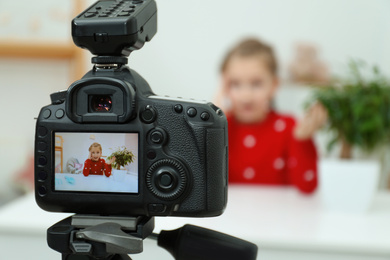 Cute little blogger with plant recording video at home, focus on camera