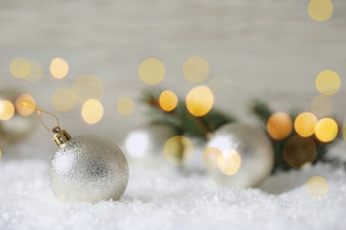 Beautiful Christmas ball on snow against blurred background, space for text. Bokeh effect