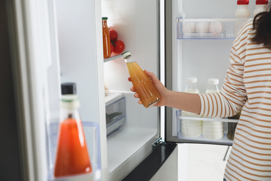 Young woman taking juice out of refrigerator, closeup