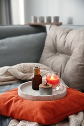 Aroma candles and oil on sofa in living room. Interior design