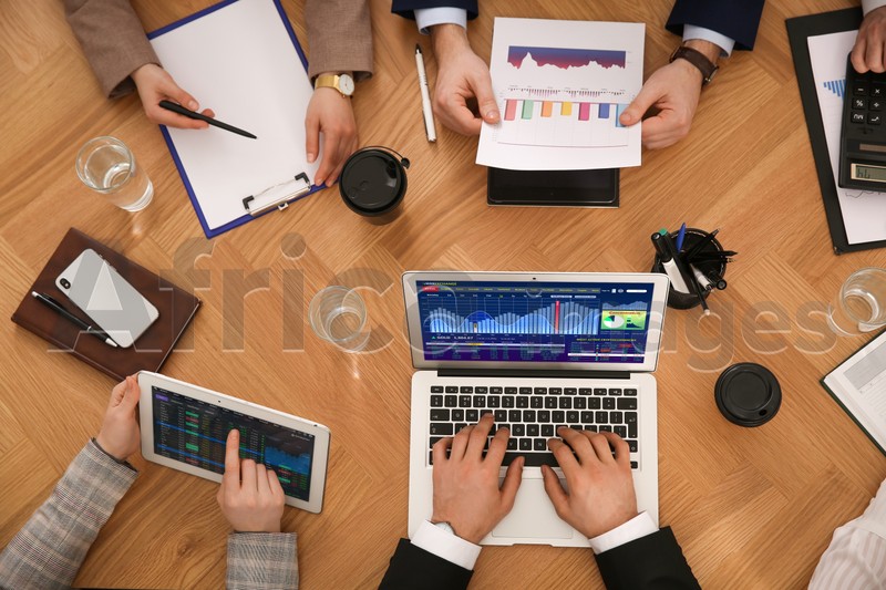 Image of People analyzing stock exchange market at wooden table, top view