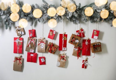 Christmas Advent calendar with gifts and decor hanging on light wall