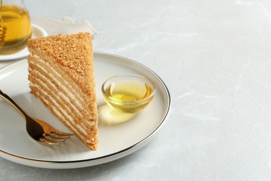 Slice of delicious layered honey cake served on grey table. Space for text