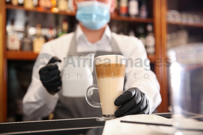 Barista preparing coffee at counter in restaurant, closeup. Catering during coronavirus quarantine