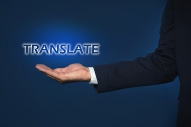 Man showing virtual model of word TRANSLATE against dark blue background, closeup