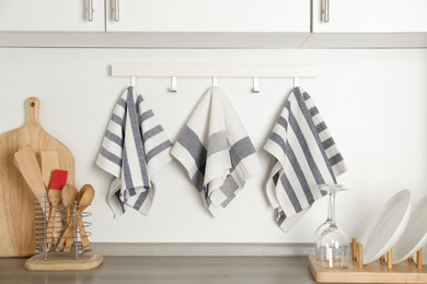 Different kitchen towels hanging on hook rack indoors