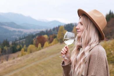 Young woman with glass of wine in peaceful mountains