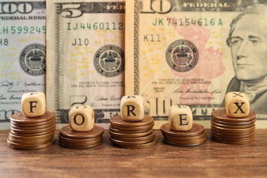 Word Forex made of wooden cubes with letters and stacked coins near banknotes on table
