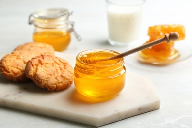 Fresh honey and cookies on white table