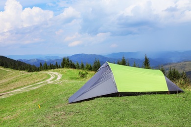 Small camping tent in mountains on sunny day