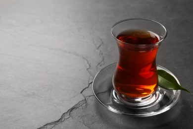 Glass with traditional Turkish tea on black table. Space for text