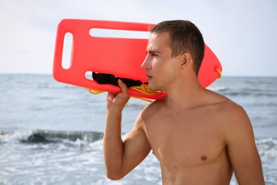 Handsome lifeguard with life buoy near sea