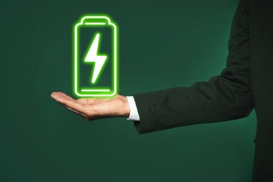Image of Businessman demonstrating at icon of charging battery on color background, closeup