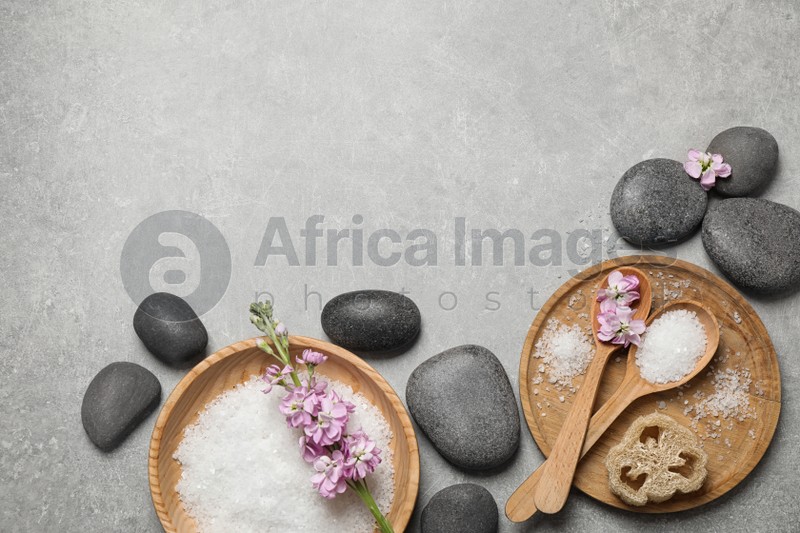 Flat lay composition with sea salt and spa stones on grey marble table. Space for text