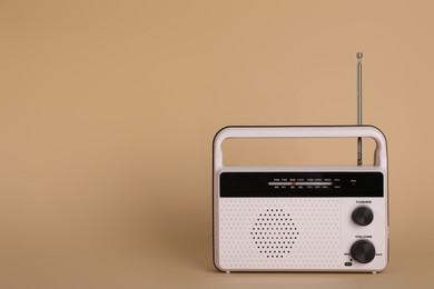 Portable retro radio receiver on beige background. Space for text