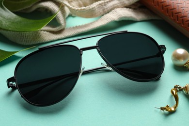 Photo of Stylish elegant sunglasses on turquoise background, closeup