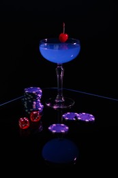Casino chips, dice and cocktail on dark background