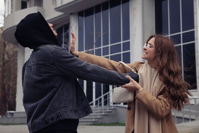 Photo of Woman fighting with thief while he trying to steal her bag on city street. Self defense concept