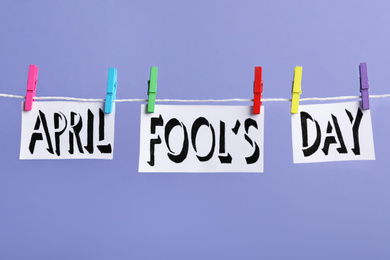 Words APRIL FOOL'S DAY with pegs on laundry line against violet background