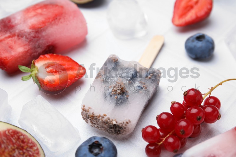 Tasty refreshing berry ice pops on white table, closeup
