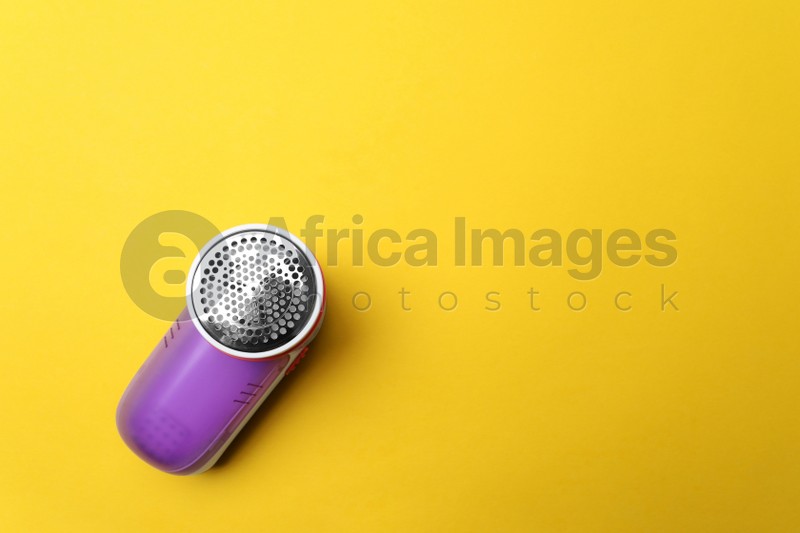 Photo of Modern fabric shaver on yellow background, top view. Space for text