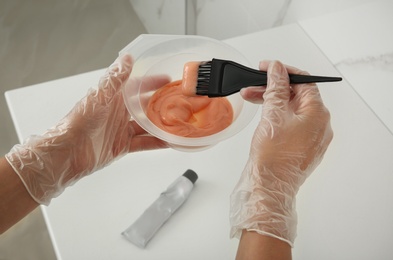 Woman preparing hair dye in bowl at home, closeup