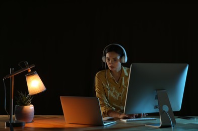 Programmer with headphones working in office at night
