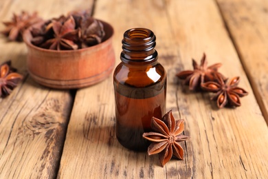 Bottle of essential oil and anise on wooden table