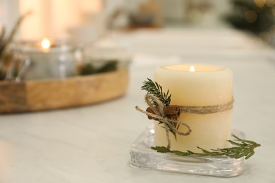 Burning scented conifer candle on white table indoors. Space for text