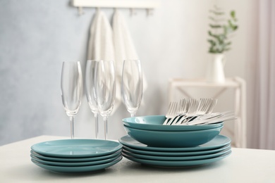 Set of clean dishware, cutlery and champagne glasses on white table indoors