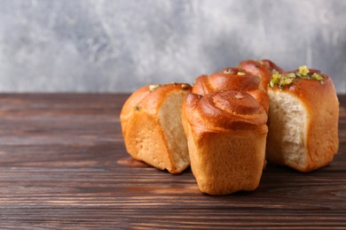 Photo of Tasty fresh pampushky. Traditional Ukrainian buns with garlic on wooden table, space for text