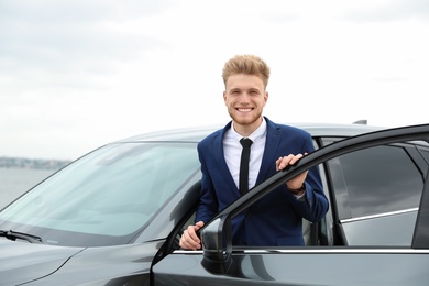 Young successful man near modern car outdoors