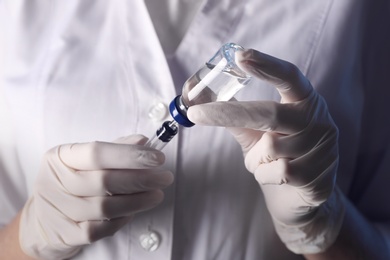 Doctor filling syringe with vaccine from vial, closeup