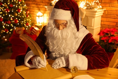 Santa Claus writing letter at table indoors