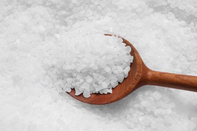 Pile of natural sea salt with wooden spoon, closeup